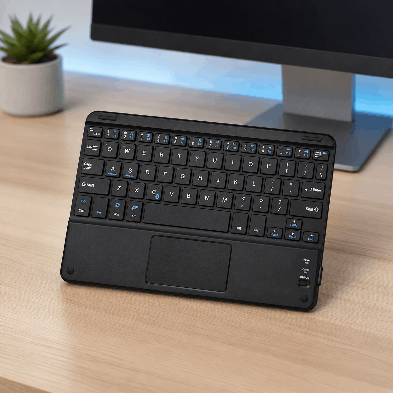 Black compact Bluetooth keyboard with built-in touchpad in a clean modern desk setup