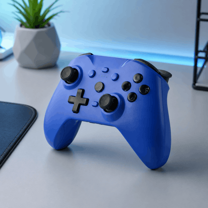 Blue ergonomic Bluetooth game controller in a clean modern desk setup with blue accent lighting